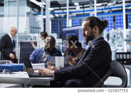 Factory scientists doing research and development, working on manufacturing automation advancements. Industrial plant experts analyze technical data during meeting, doing strategic production planning Factory scientists doing research and development, working on manufacturing automation advancements. Industrial plant experts analyze technical data during meeting, doing strategic production planning 125857753