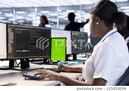 Server room computer scientist using green screen tablet to find firewall misconfigurations. IT specialist checking systems bottlenecks leading to sluggish data transfer rates using mockup device 125858034