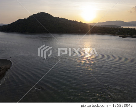 Drone shot of tropical bay with sailboats and lush island scenery, beautiful seaside landscape featuring a tranquil rocky beach with harbor and clear blue waters. Exotic shoreline scenery. 125858042