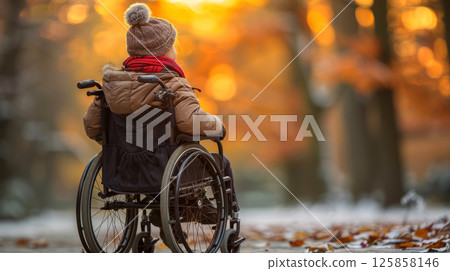 young woman sits in a wheelchair wearing headphones and listening to music. 125858146