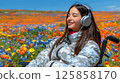 young woman sits in a wheelchair wearing headphones and listening to music. 125858170