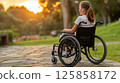 young woman sits in a wheelchair wearing headphones and listening to music. 125858172