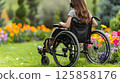young woman sits in a wheelchair wearing headphones and listening to music. 125858176