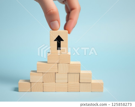 Hand Stacking Wooden Blocks with Upward Arrows 125858273