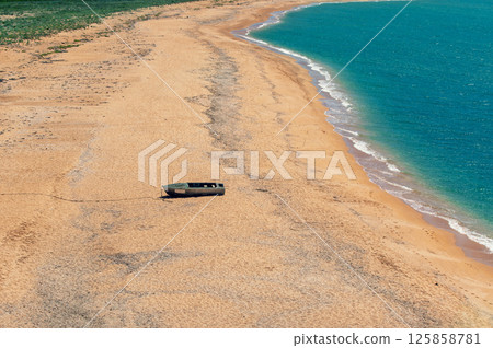 Top view of the sandy seashore. Lonely boat on a sandy beach 125858781