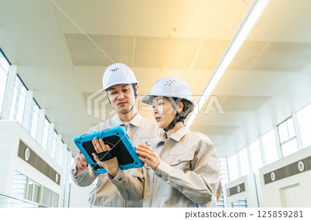 Male and female engineers inspecting the interior of a building while looking at a tablet PC Male and female engineers inspecting the interior of a building while looking at a tablet PC 125859281