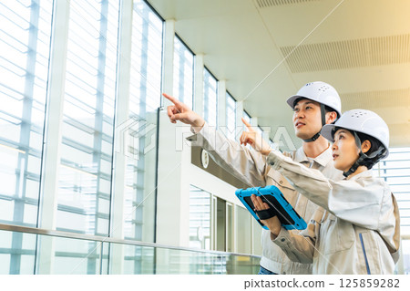 男性工程師和女工程師一邊查看平板電腦，一邊檢查建築物內部 125859282