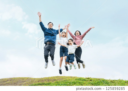 A family jumping energetically under the blue sky 125859285