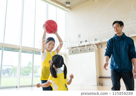 Children playing basketball and a man coaching them Children playing basketball and a man coaching them 125859289