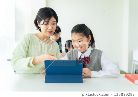 A female teacher instructing a girl using a tablet 125859292