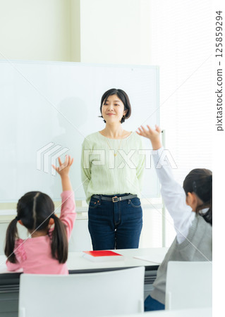 A female teacher teaching children in a classroom 125859294