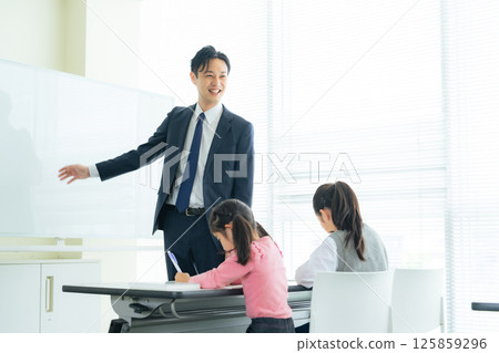 A male teacher teaching children in a classroom 125859296