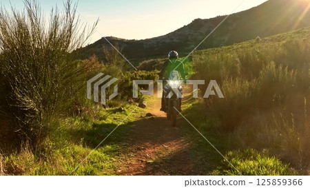Man, professional motorcyclist in full moto equipment riding crops enduro bike on mountain road at sunset. Concept of motosport, speed, hobby, journey, activity Man, professional motorcyclist in full moto equipment riding crops enduro bike on mountain road at sunset. Concept of motosport, speed, hobby, journey, activity 125859366