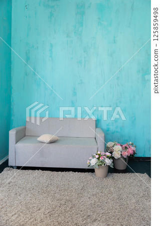 Gray sofa with a vase of flowers in the interior of a blue room Gray sofa with a vase of flowers in the interior of a blue room 125859498