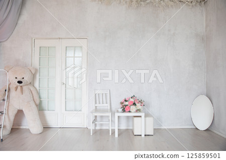 Table with a vase of flowers and a bear toy in the interior of a room Table with a vase of flowers and a bear toy in the interior of a room 125859501