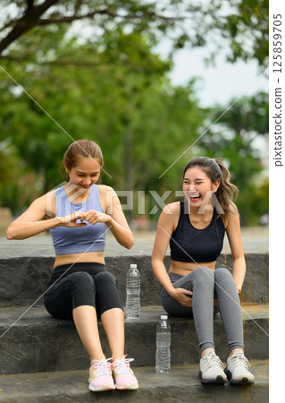 Cheerful female friends resting together after exercising outdoors 125859705