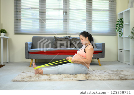 Pregnant woman exercising with resistance band staying active and healthy during pregnancy 125859731