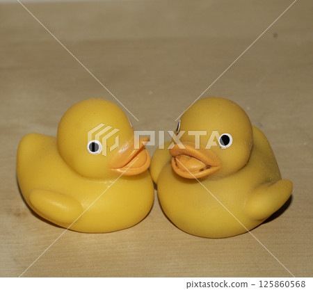 Two Cute Toy Yellow Rubber Ducks Looking Jolly on a Wood Shelf 125860568