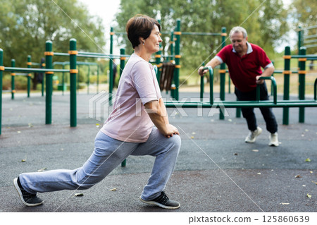 Elderly woman doing gymnastics on an outdoor sports ground 125860639