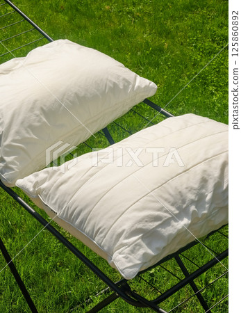 White pillows drying on outdoor rack in sunlight over green grass on summer day. High quality photo White pillows drying on outdoor rack in sunlight over green grass on summer day. High quality photo 125860892