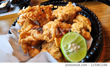 Crispy Deep-Fried Chicken Bites with Fresh Lime Garnish Crispy Deep-Fried Chicken Bites with Fresh Lime Garnish 125861286