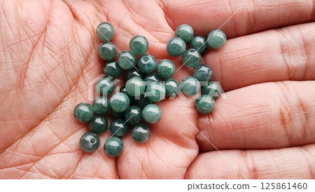Green Stone Beads in Hand Showcasing Natural Gemstone Beauty Green Stone Beads in Hand Showcasing Natural Gemstone Beauty 125861460