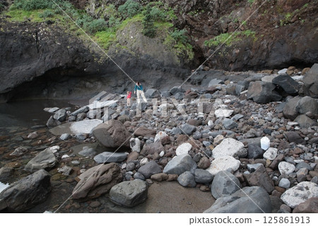 Mother and child exploring rocky coastline in ribeira da janela, madeira 125861913