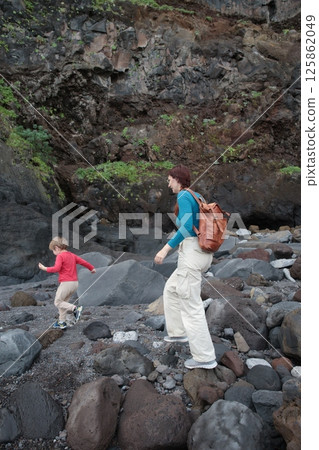 Mother and son hiking on volcanic rocks exploring nature together 125862049