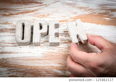 Open. Concrete alphabet letters on a light painted wood texture background 125862117