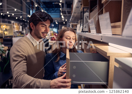 Couple explores various modern furniture options in stylish store highlighting unique designs Couple explores various modern furniture options in stylish store highlighting unique designs 125862140