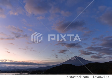 Textured clouds illuminated by the fading sunlight, while Mount Fuji silhouette rises below 125862183