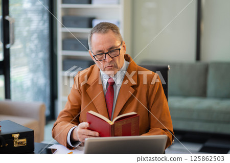 Lawyer middle age is sitting at the pensive reading law table. Lawyer middle age is sitting at the pensive reading law table. 125862503
