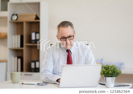Mature businessman calculate and analyzing graph document financial with report and laptop in office. Mature businessman calculate and analyzing graph document financial with report and laptop in office. 125862564