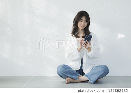 A young woman operating a smartphone A young woman operating a smartphone 125862585