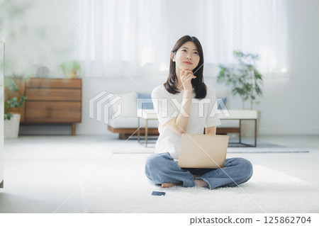 Young woman using a computer in the living room Young woman using a computer in the living room 125862704