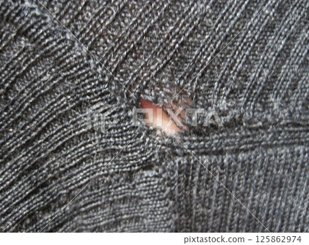 A wool sweater with holes eaten by moths A wool sweater with holes eaten by moths 125862974