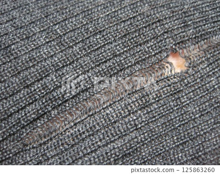 A wool sweater with a run in it due to a moth hole A wool sweater with a run in it due to a moth hole 125863260