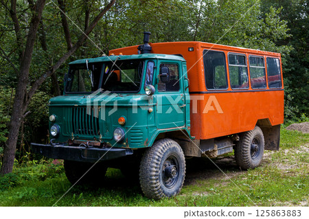Old off-road truck with green cabin and orange passenger body Old off-road truck with green cabin and orange passenger body 125863883