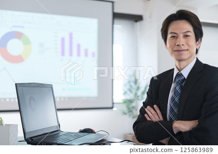 一位身著西裝、雙手交叉坐著的年輕人 125863989