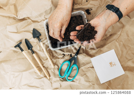 Kraft paper background, fertile soil and garden tools, top view. Hands planting seeds Kraft paper background, fertile soil and garden tools, top view. Hands planting seeds 125864088