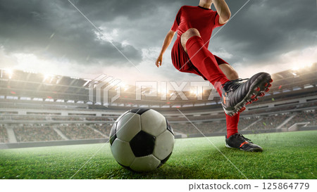 Cropped image of soccer player in red uniform during intense outdoor game, kicking ball against stormy sky. 3D render of stadium. 125864779