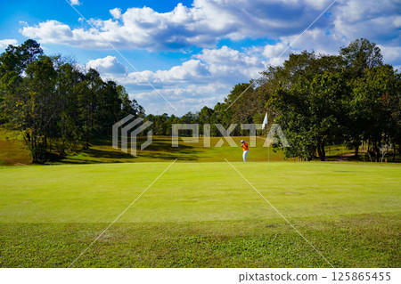Golfer playing golf in the evening golf course, on sun set evening time. Golfer playing golf in the evening golf course, on sun set evening time. 125865455
