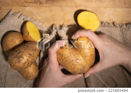 Explore the Unique Potato Shapes in Hands Set Against a Beautiful Rustic Background 125865494