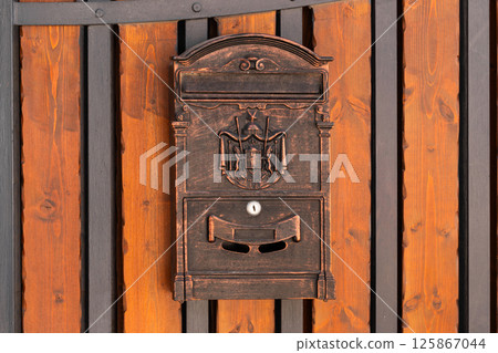 Ornate Black Mailbox Mounted on Wooden Gate Ornate Black Mailbox Mounted on Wooden Gate 125867044