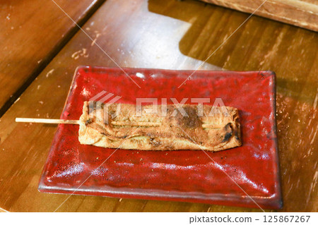 close up of Cantonese skewer grilled tofu skin on a red plate in a wooden table  close up of Cantonese skewer grilled tofu skin on a red plate in a wooden table  125867267