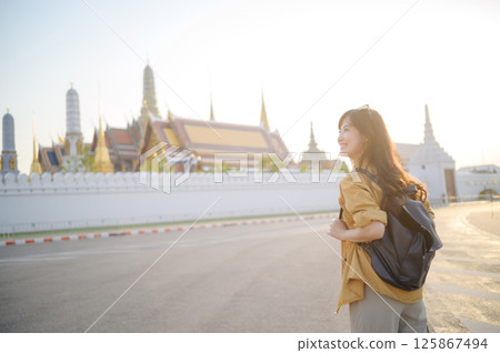 Southeast asian woman travel concept with backpack smiling near temple in bright sunlight for vacation and adventure Southeast asian woman travel concept with backpack smiling near temple in bright sunlight for vacation and adventure 125867494