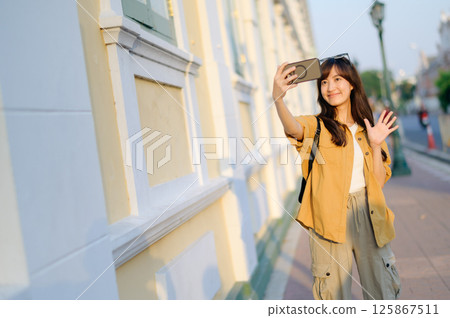 Southeast asian woman takes selfie while travel exploring city street, capturing joyful moment that reflects travel concept and her happy expression Southeast asian woman takes selfie while travel exploring city street, capturing joyful moment that reflects travel concept and her happy expression 125867511