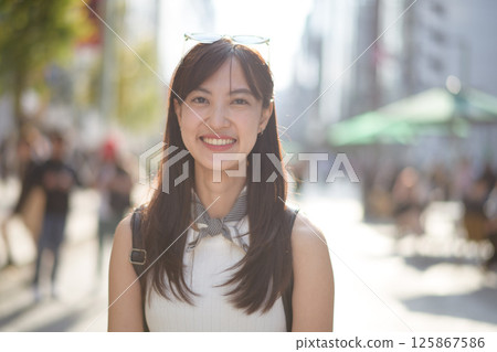 Southeast asian woman smiling outdoors in city street with sunlight and blurred background showing happiness and casual style Southeast asian woman smiling outdoors in city street with sunlight and blurred background showing happiness and casual style 125867586