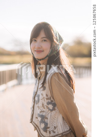 Southeast asian woman smiles gently while travel outdoors wearing floral vest and headscarf capturing peaceful travel concept in soft natural light Southeast asian woman smiles gently while travel outdoors wearing floral vest and headscarf capturing peaceful travel concept in soft natural light 125867658