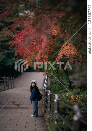 Southeast asian woman enjoys travel concept walking on stone stairs under colorful autumn leaves feeling peaceful and connected with nature in serene outdoor setting Southeast asian woman enjoys travel concept walking on stone stairs under colorful autumn leaves feeling peaceful and connected with nature in serene outdoor setting 125867705